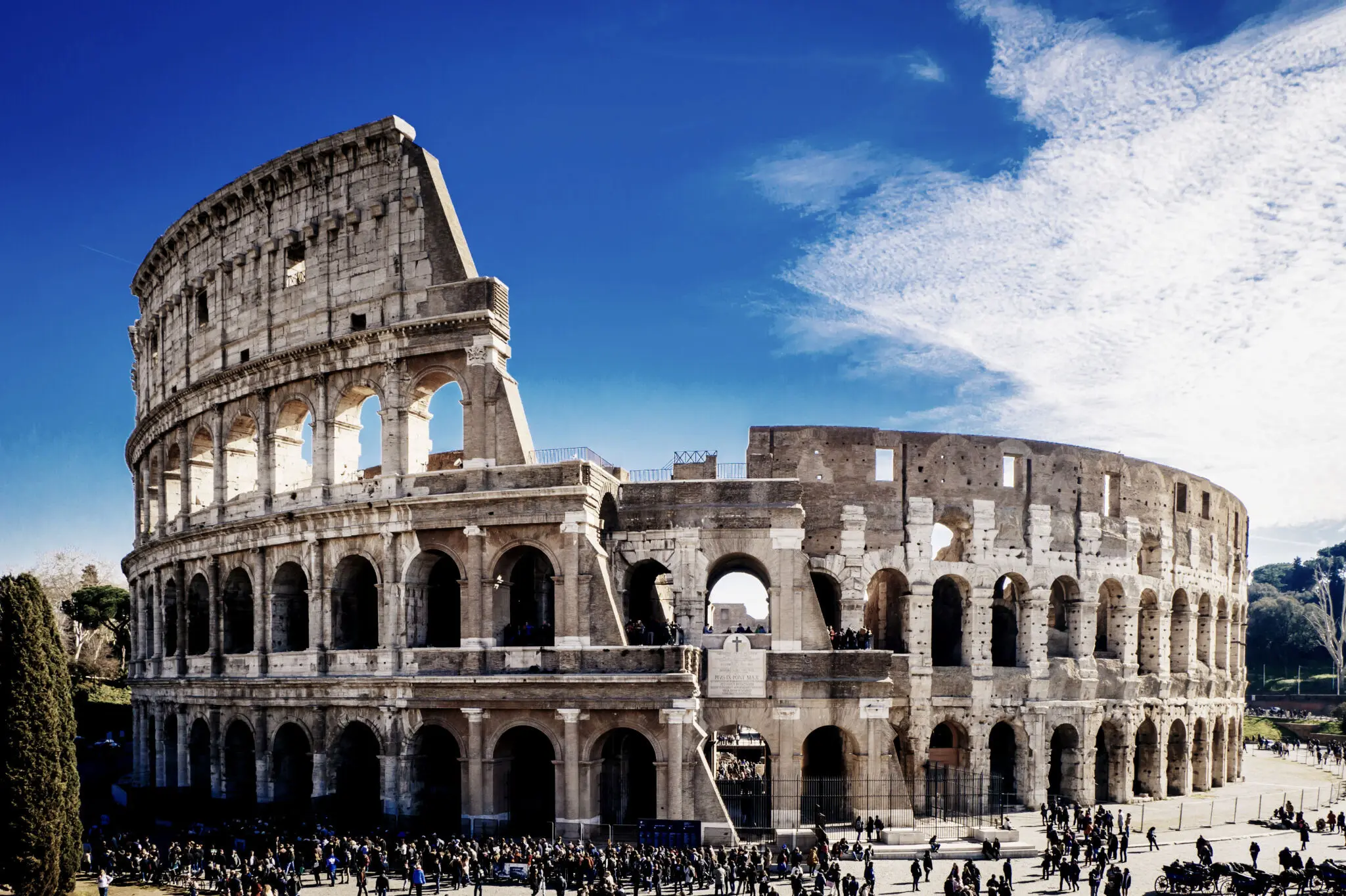 Detailed view of the Roman Colosseum's ancient stone arches under a bright blue sky, representing Landmark Global's delivery destination in Italy.